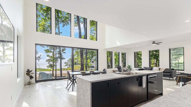 Una cocina moderna con ventanas amplias, una isla central y un comedor con sillas.