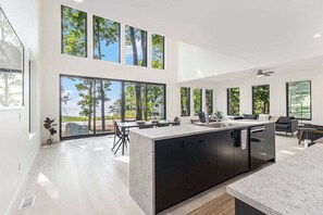 Una cocina moderna con ventanas amplias, una isla central y un comedor con sillas.