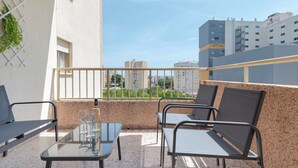 Ein Balkon mit Glastisch, zwei Stühlen und einer Wasserflasche.