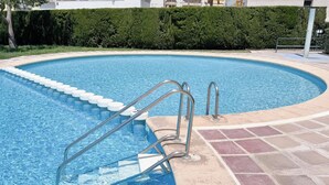 Ein Schwimmbecken mit Stufen zum Wasser, umgeben von einer gefliesten Terrasse.