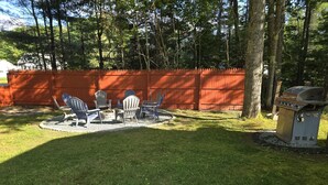 A backyard with a fire pit, Adirondack chairs, and a grill. - Elma-Vista Spacious 3-bedroom apartment with WiFi and AC in charming Ellsworth (Ellsworth)