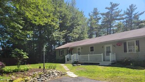 A single-story house with a front porch, a small garden with rocks and plants, and a clear sky. - Elma-Vista Spacious 3-bedroom apartment with WiFi and AC in charming Ellsworth (Ellsworth)