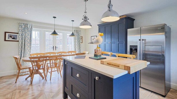 Una cocina moderna con una isla central, un refrigerador de acero inoxidable e iluminación colgante.