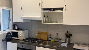 A modern kitchen with white cabinets, a gas stove, a microwave, and a built-in oven.