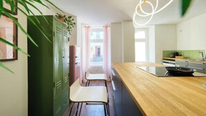 Una cocina moderna con encimera de madera, dos taburetes blancos y un armario verde.