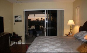 A hotel room with a bed, a desk, a chair, a lamp, and a sliding glass door leading to an outdoor area. - Cape Coral Wildlife Views
Heated Pool-Pet & Family Friendly (Cape Coral)