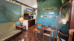 Una habitación acogedora con un sofá, una mesita, una silla, un televisor y una zona de cocina.