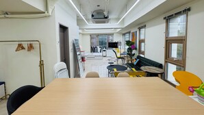 Un espacio de oficina moderno con una mesa larga, sillas, un escritorio con computadora y un ventanal grande.