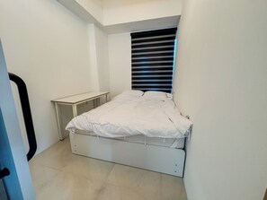A small, neatly arranged bedroom with a single bed, a bedside table, and a window with blinds. - 사Atelier Seongsu Riverside Loft Cherry Blossom Road Han River airport bus (Seoul)