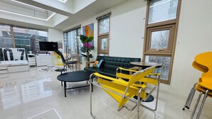 Una habitación moderna y luminosa con una cama grande, un sofá verde, un sillón amarillo y un comedor con mesa y sillas.