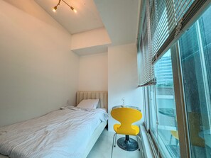 A bedroom with a bed, a chair, and a window with blinds. - 사Atelier Seongsu Riverside Loft Cherry Blossom Road Han River airport bus (Seoul)