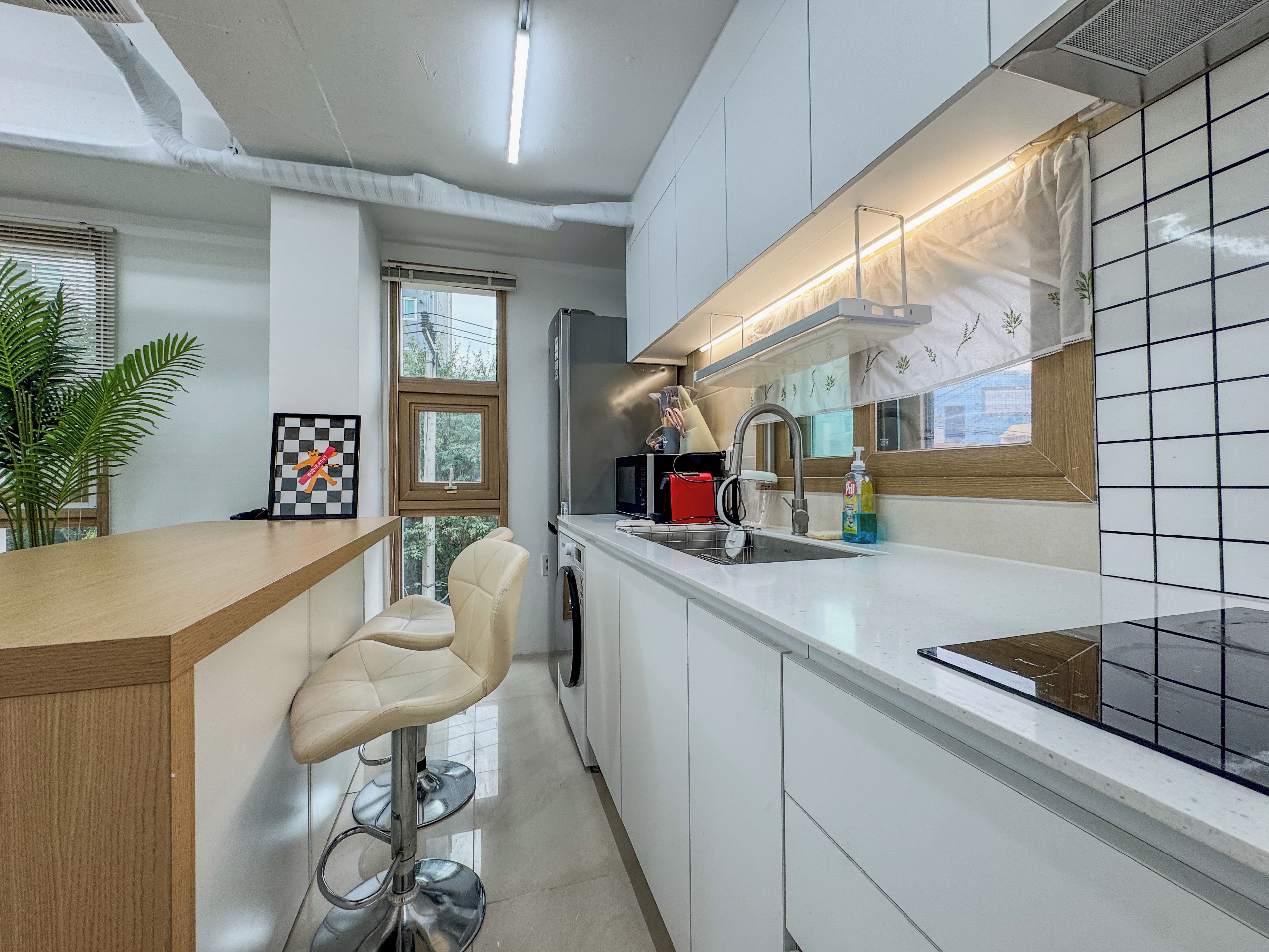 A modern kitchen with a bar area, a built-in oven, and a window providing natural light.