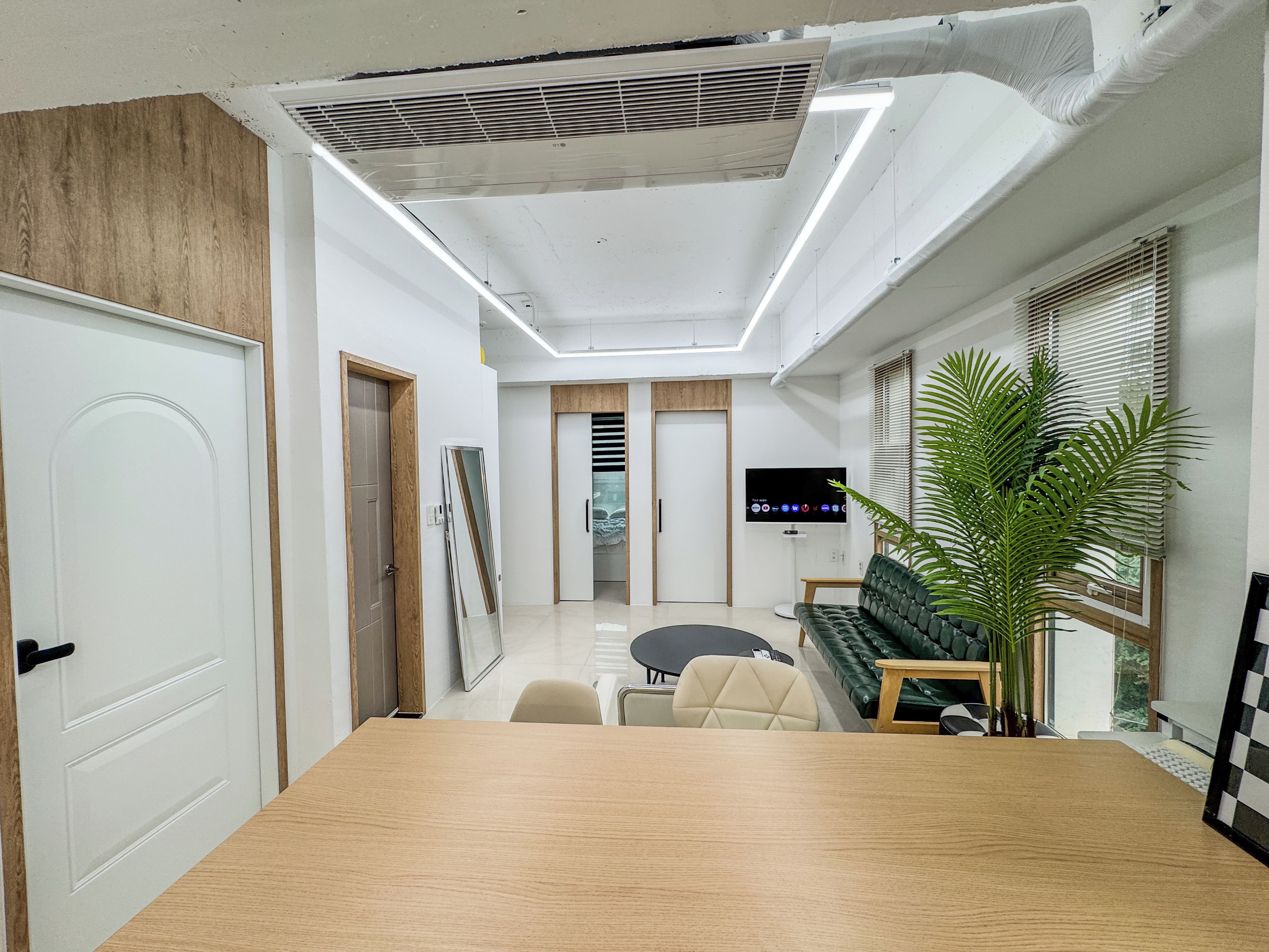 A modern interior with a wooden conference table, a sofa, and a television.