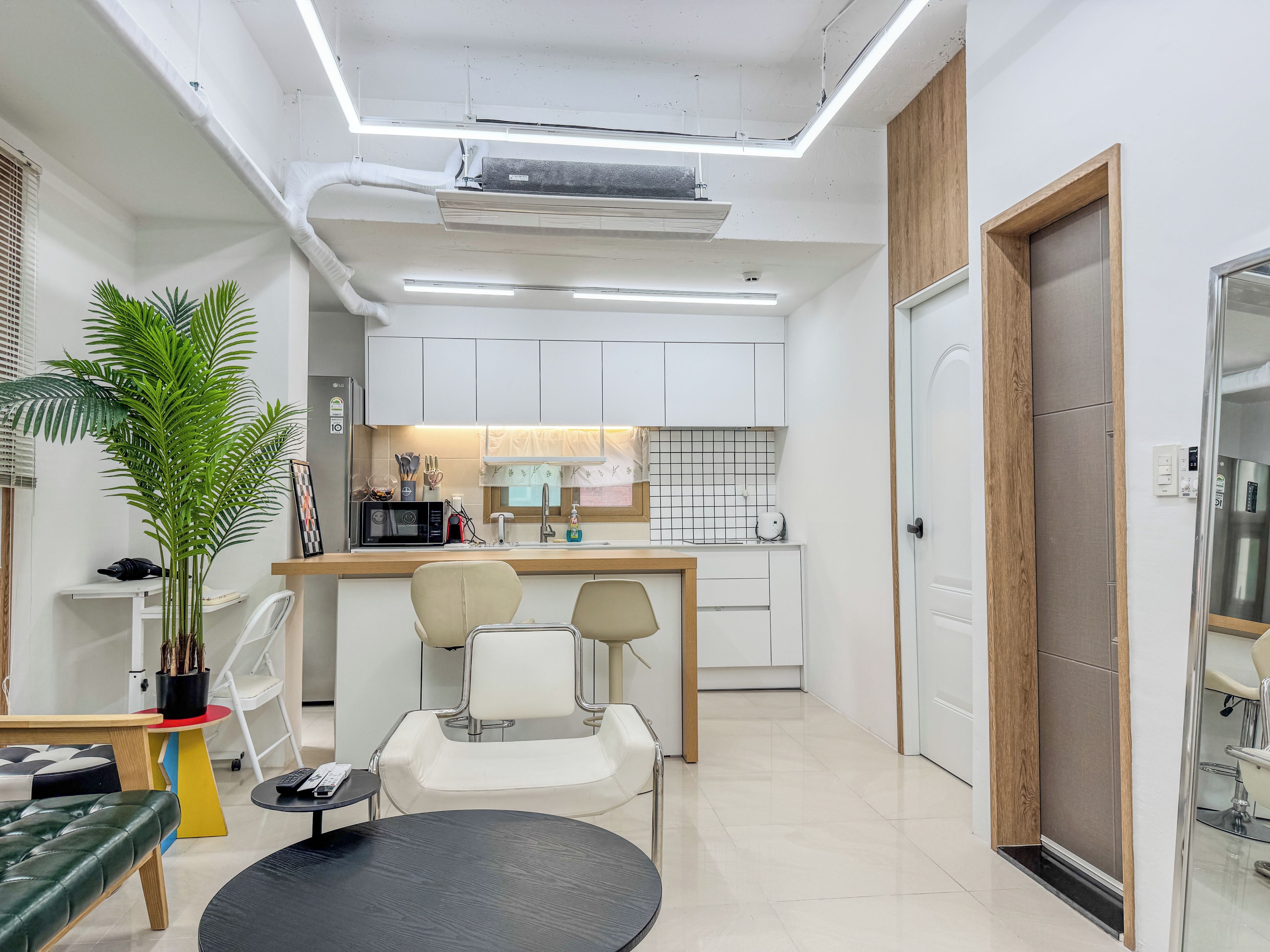 A modern kitchen with white cabinets, a central island, and a dining area with a round table and two chairs.