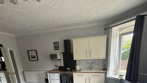 Una cucina moderna con mobili bianchi, una cappa aspirante nera e una finestra con tende.