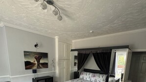 Una camera da letto con un letto, un divano in pelle marrone, un quadro appeso al muro e una ventola a soffitto.