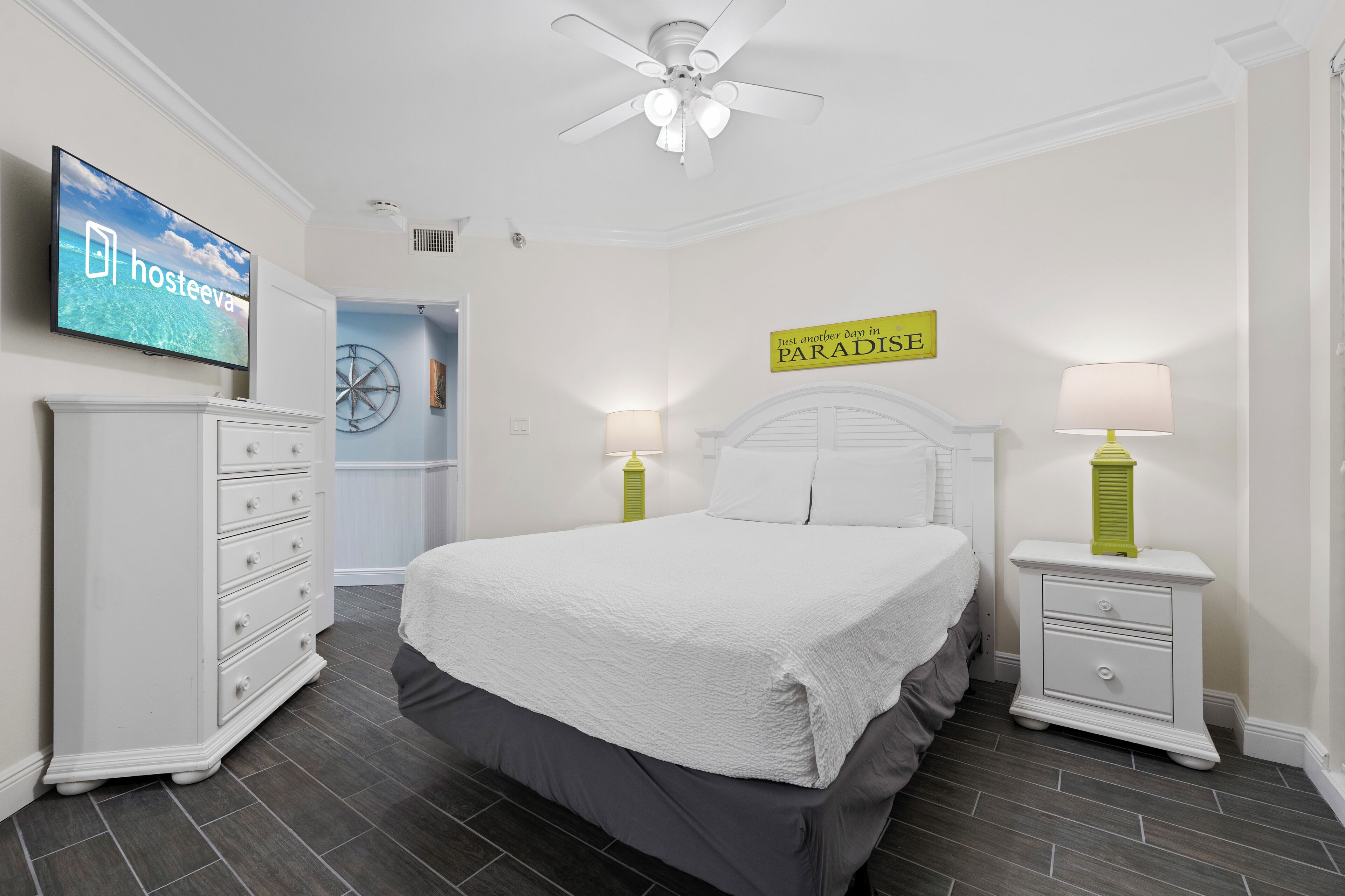 Een slaapkamer met een bed, een dressoir, een nachtkastje, een televisie en een bord aan de muur.