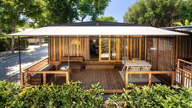 A wooden outdoor patio with a table and chairs, a bench, and a covered seating area. - TAIGA Tarifa Valdevaqueros (Tarifa)