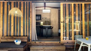 A wooden cabin interior with a dining area, a kitchen, and a seating area with a woven light fixture. - TAIGA Tarifa Valdevaqueros (Tarifa)