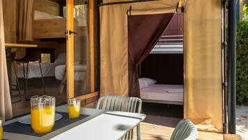 Una habitación acogedora y bien iluminada con una litera, una mesa con una silla y un vaso de jugo de naranja.