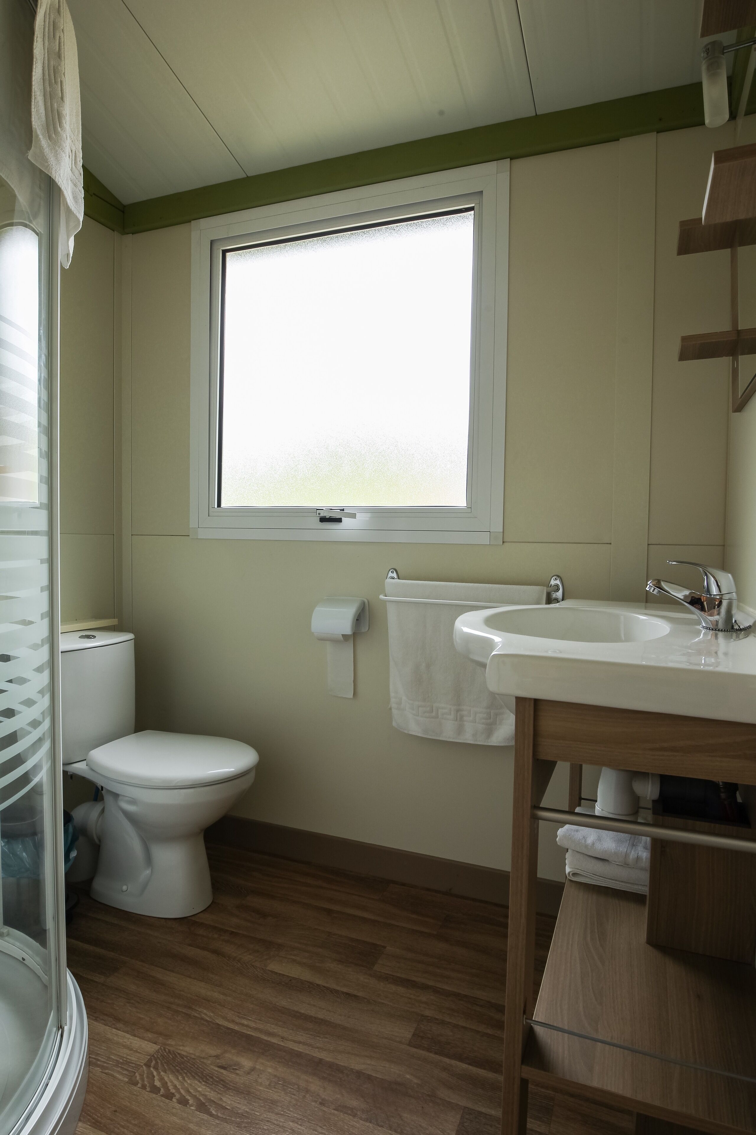 Et badeværelse med toilet, håndvask og vindue.