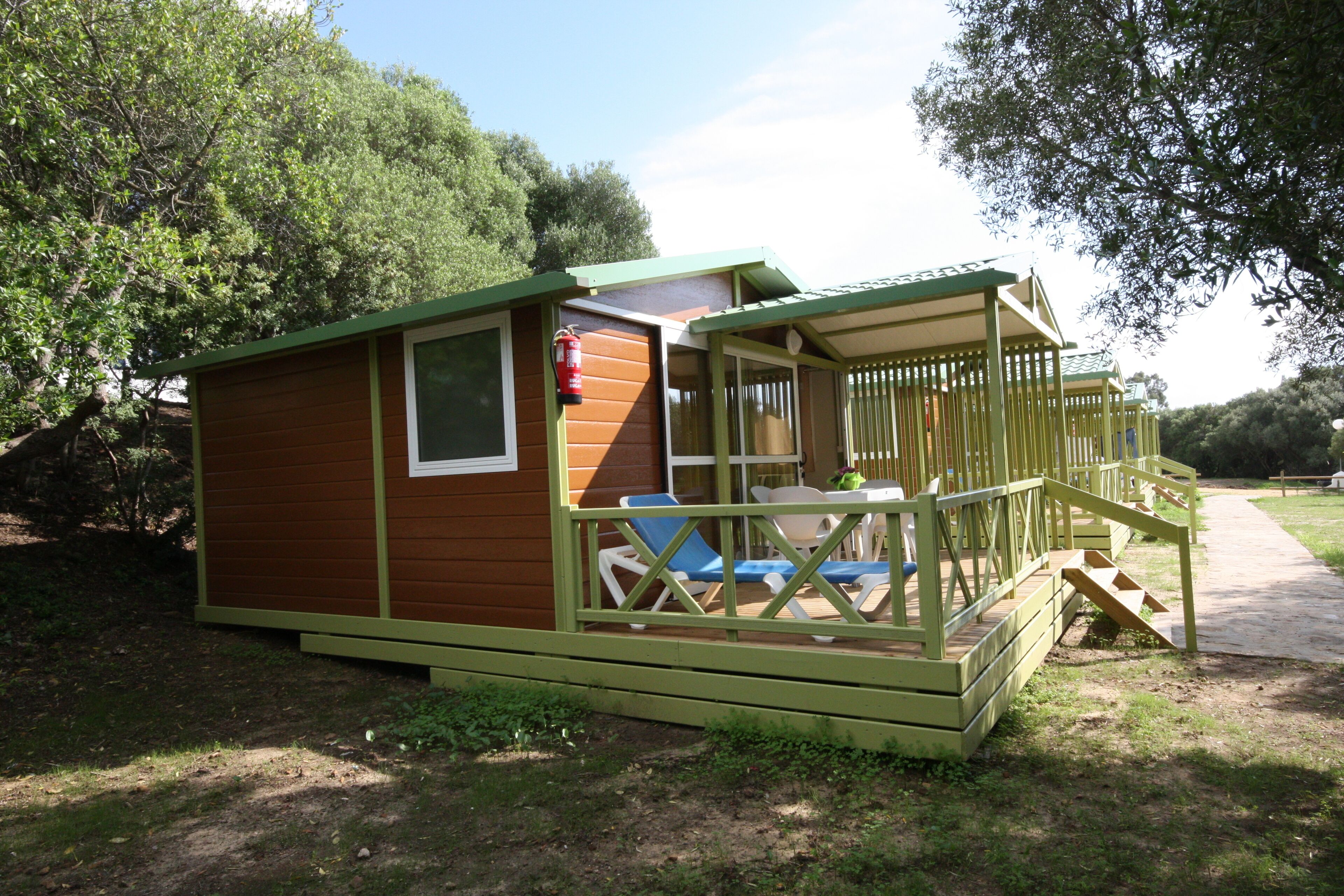Una cabaña de madera pequeña con porche y zona de estar al aire libre.