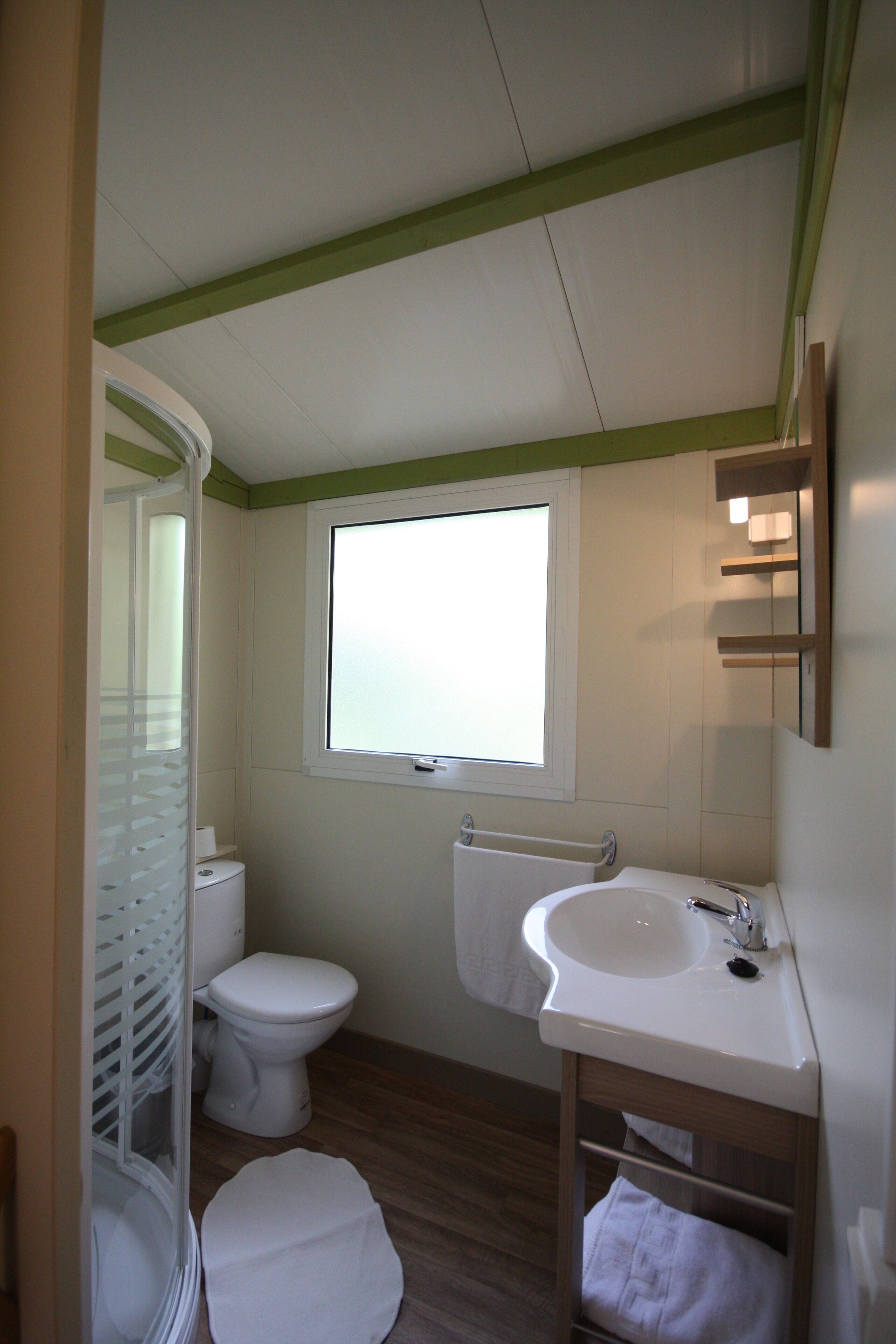 A small bathroom with a toilet, sink, and window.