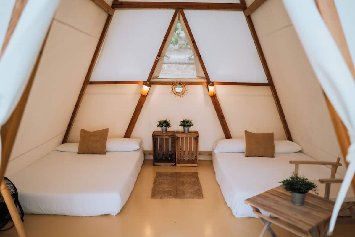 A cozy tent with two beds, a small table, and a window.