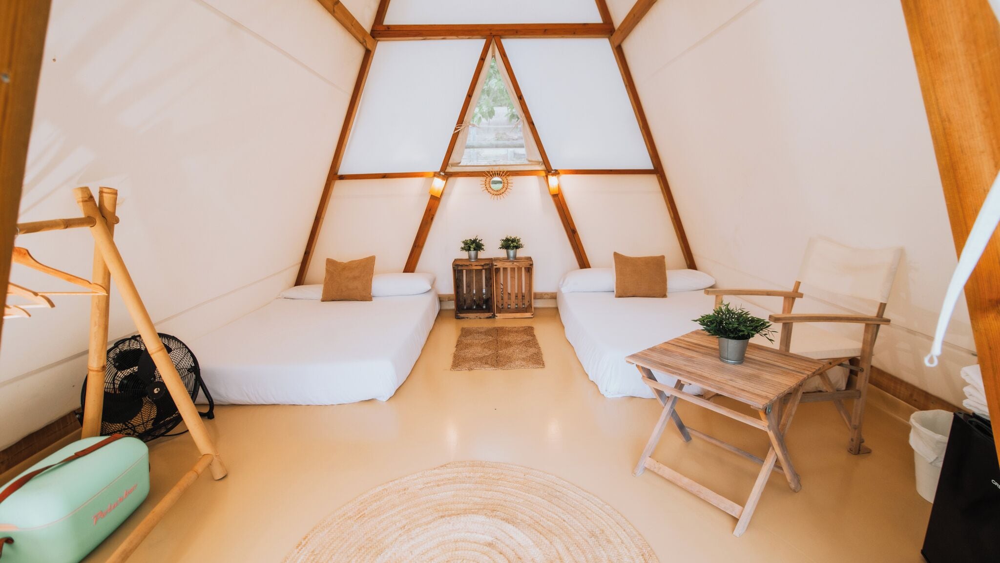 Une pièce confortable, aménagée comme une tente triangulaire, avec deux lits, une petite table et une chaise.