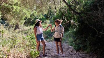 Dos personas caminando por un sendero de tierra rodeado de vegetación.