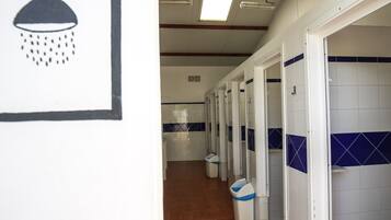 A hallway with multiple stalls, each with a white tiled wall and a blue accent.