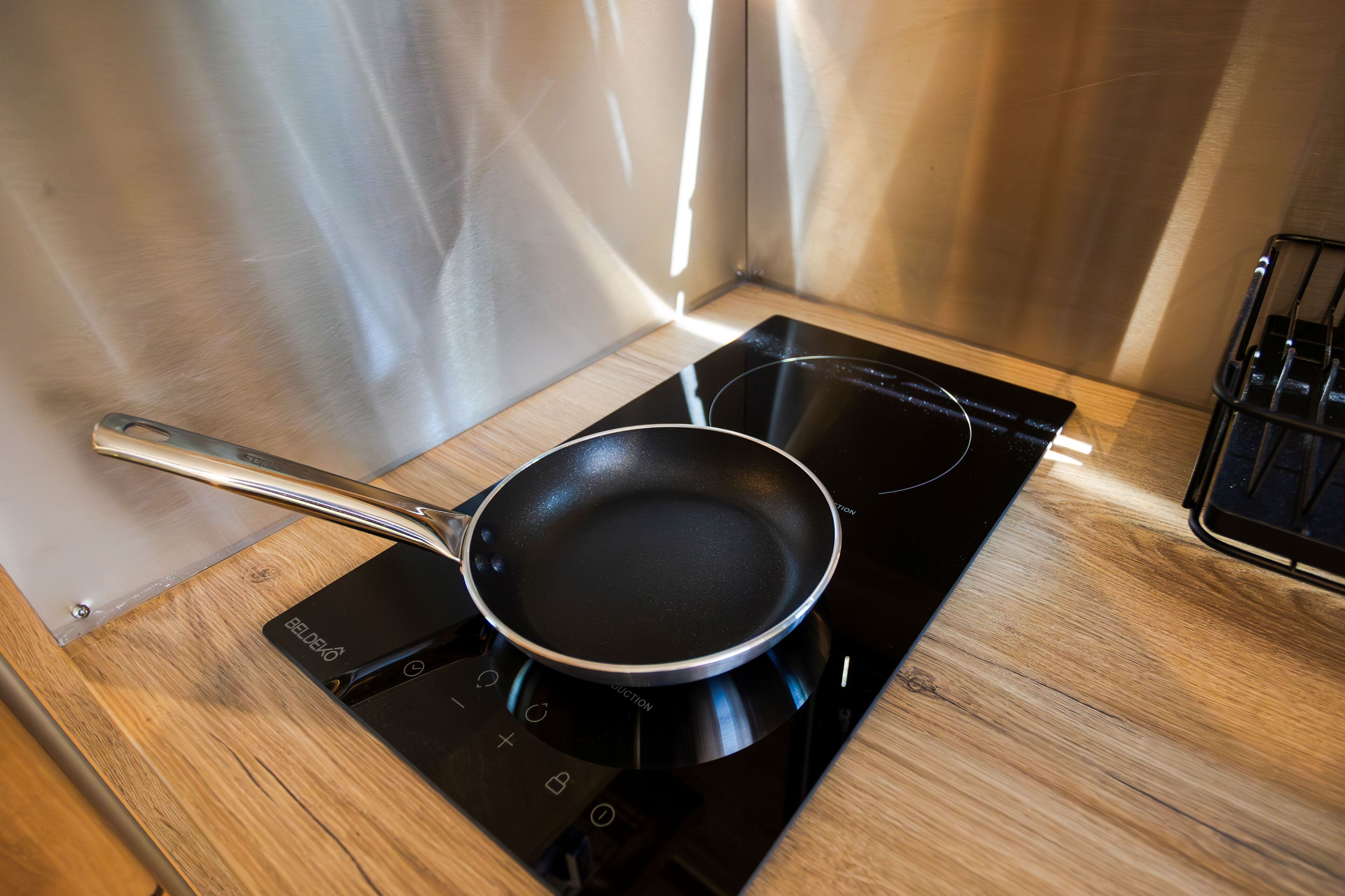 Een keuken met een zwart inductiekookplaatje en een koekenpan erop.