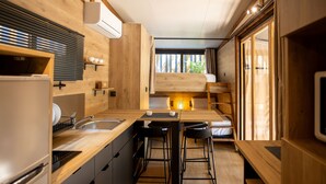 A compact kitchen with wooden cabinetry, a sink, and a dining area with stools. - TAIGA Tarifa Valdevaqueros (Tarifa)
