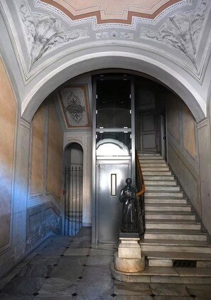 Eine prächtige Treppe mit einer Statue unten, die zu einer Tür mit einer Glasscheibe führt.