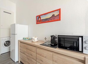 Eine Küchenzeile mit einer Mikrowelle, einer Kaffeemaschine und einem Landschaftsbild.