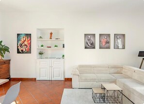 Ein Wohnzimmer mit Ecksofa, Couchtisch, weißem Schrank und Wandbildern.