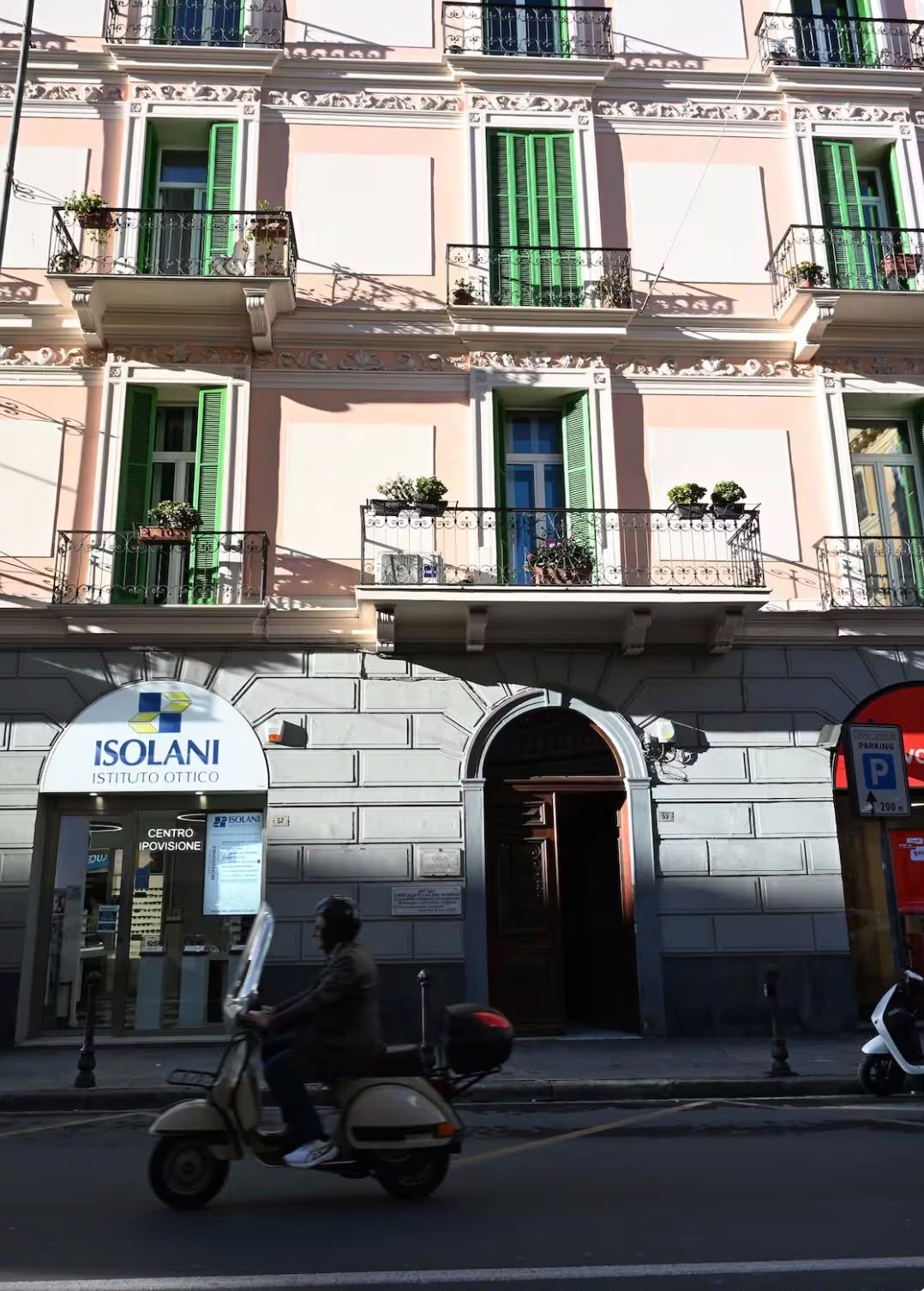 A building with a sign for 'ISOLANI ISTITUTO OTTICO CENTRO PROVISIONE' and a parking sign indicating 200 meters.