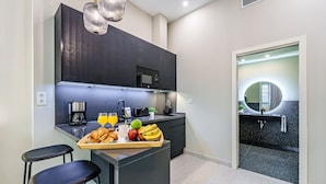 Una cocina moderna con armarios oscuros, una bandeja de desayuno con croissants, fruta y jugo, y una pequeña barra con taburetes.