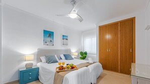 Ein Hotelzimmer mit einem Bett, einem Nachttisch, einem Holzschrank und einem Deckenventilator.