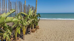 Ein Sandstrand mit einer Holzumzäunung und Bananenstauden.