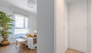 A modern hotel room with a dining area, a large window, a potted plant, and a white wardrobe. - Sunset Malaga Apartments - IBARRA (Málaga)