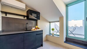 A modern kitchen with dark cabinetry, a built-in microwave, and a window overlooking a white building.