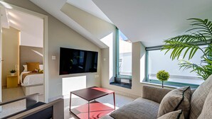 Un salon moderne doté d’un téléviseur à écran plat, d’une petite table, d’un canapé et d’une grande fenêtre offrant une vue dégagée.