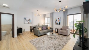 Een moderne woonkamer met een grijze bank, een salontafel en een televisie op een meubel.