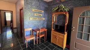 Um quarto com piso de azulejos, um armário de madeira com espelho, uma mesa pequena com cadeiras e uma porta com painel de vidro jateado.