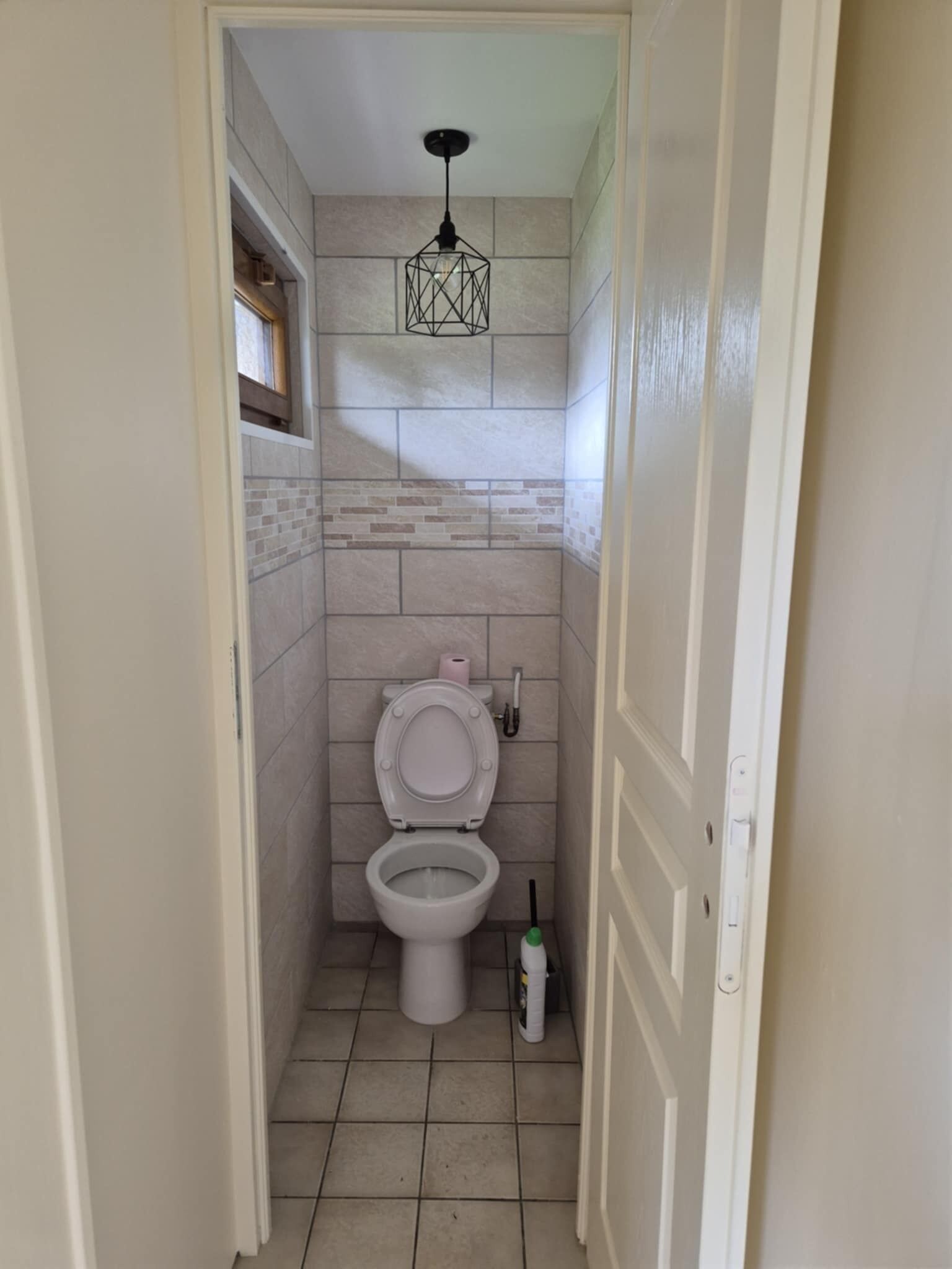 Ein kleines Badezimmer mit Toilette, einem Handtrockner und einer Seifenspenderflasche.