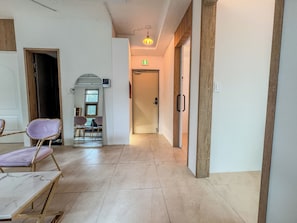 Un couloir d’hôtel avec un sol carrelé en marbre, un comptoir de réception et un espace détente avec des fauteuils.