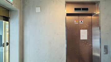 An elevator with a digital display, emergency exit sign, and safety instructions.