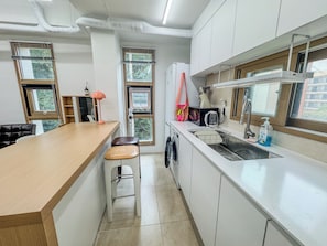 A modern kitchen with a wooden countertop, a sink, and a washing machine. - 삼Atelier Seongsu Riverside Loft Cherry Blossom Road Han River airport bus (Seoul)