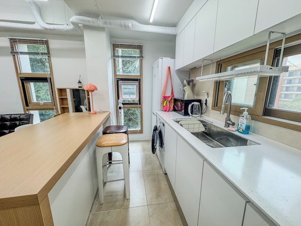 Une cuisine moderne avec un plan de travail en bois, un évier et un lave-linge.